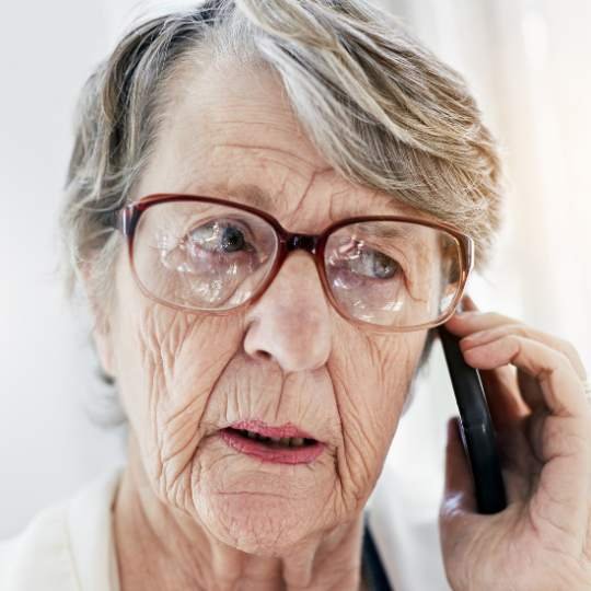 idosa desconfiada falando no telefone