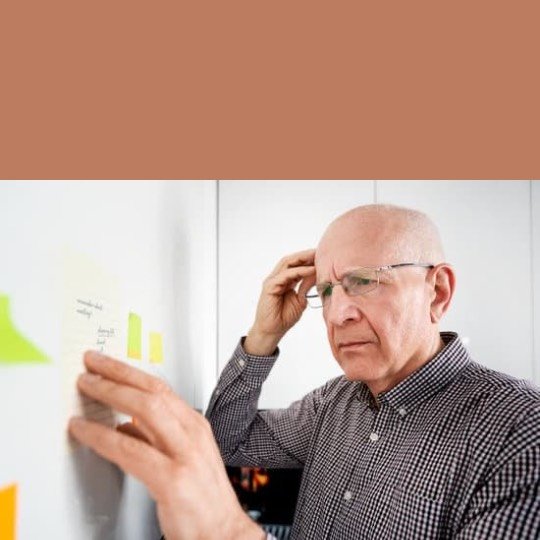a man looking at a sticky note on a white board