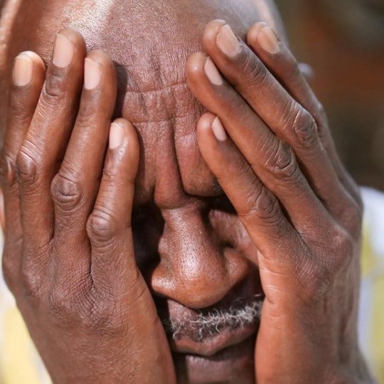 Idoso com dores e mãos nos olhos