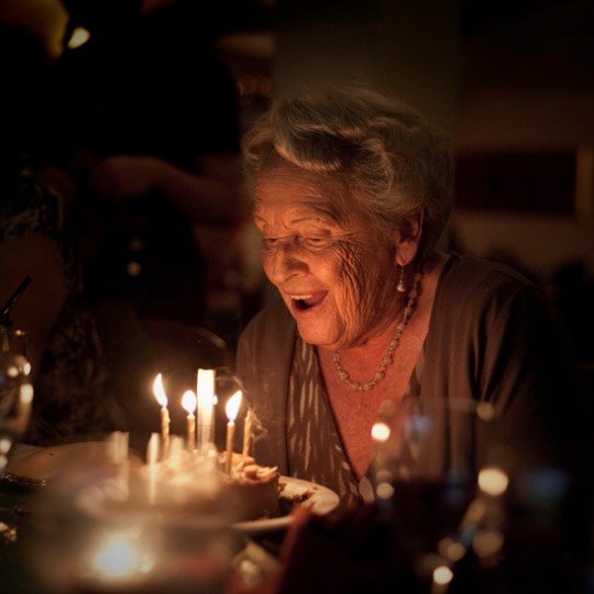 Idosa soprando vela de aniversário
