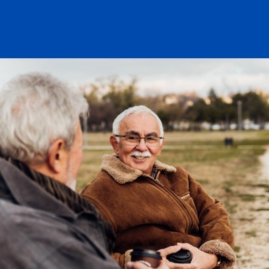 Idosos conversando sentados em praça