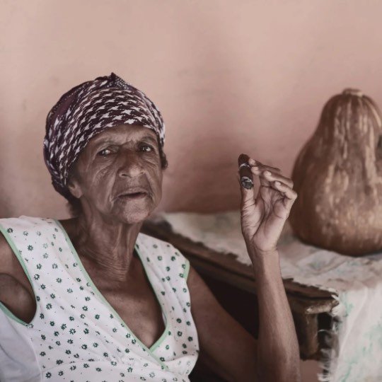 Idosa posando para foto fumando um cigarro