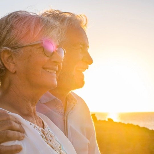 Imagem de casal de idoso em silhueta mirando o sol