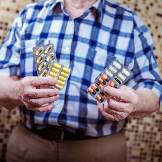 Idoso segurando cartela de suplementos vitamínicos