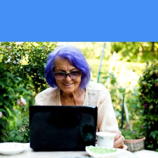 Idosa sorrindo em frente ao notebook