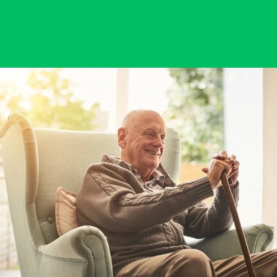 Idoso sentado, apoiado na bengala com semblante feliz