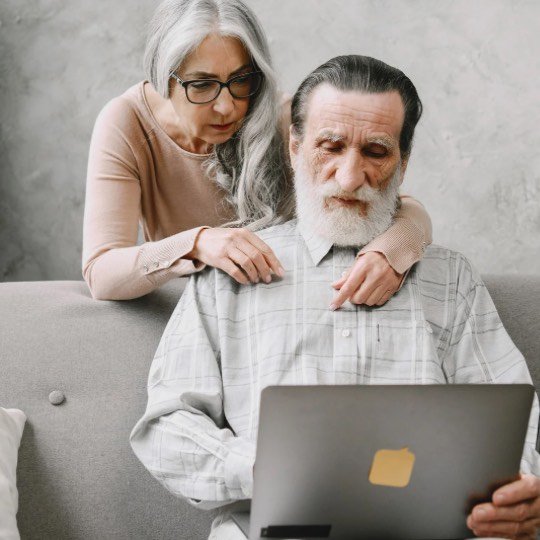 Casal de idosos manuseando computador